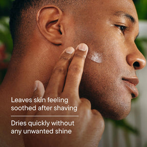 Close-up of a man's face and hand applying or smoothing a white cream onto his cheek, with overlaid text reading 'Leaves skin feeling soothed after shaving' and 'Dries quickly without any unwanted shine'.