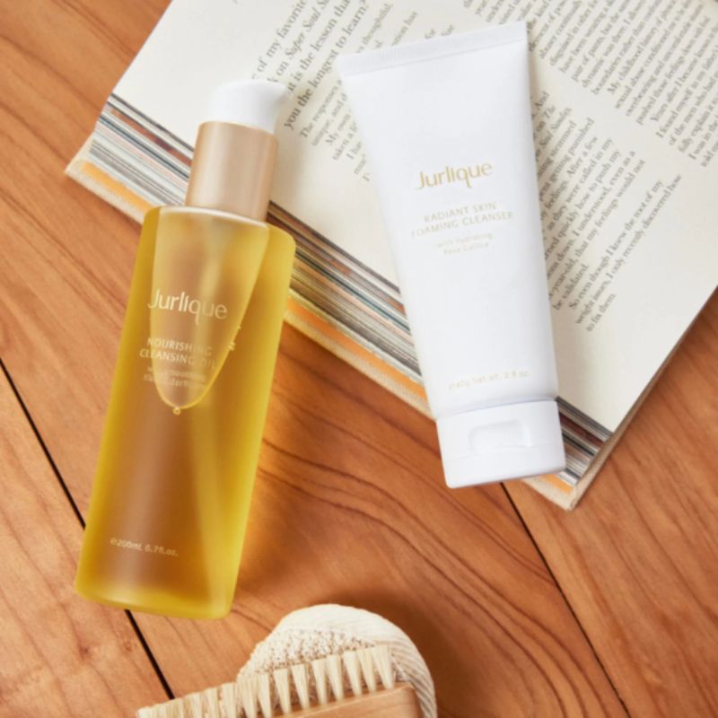 Jurlique skincare products on a wooden surface with a book underneath